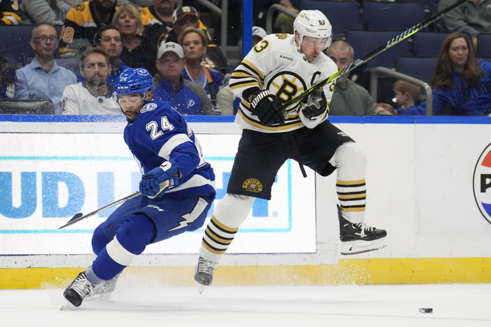 Boston Bruins left wing Brad Marchand (63) slips past a check by Tampa Bay Lightning defenseman Matt Dumba (24) during the first period of an NHL hockey game Wednesday, March 27, 2024, in Tampa, Fla. (AP Photo/Chris O'Meara)