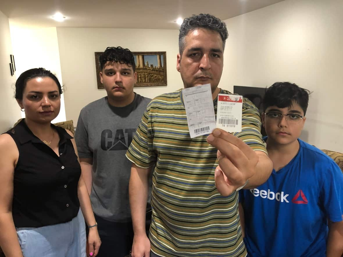 Moe Abdollahi, second from right, holds the two luggage claim checks that go with the two bags lost on a recent Air Canada flight. His wife, Kimia Pirmoradi, left, and sons Amir, second from left, and Yashar are awaiting items left in the bags.  (Dale Molnar/CBC - image credit)