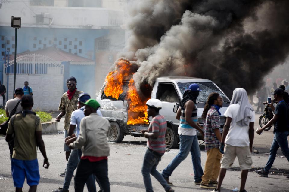 Smoke billows from a van set fire by protesters during clashes with police amid a protest demanding the resignation of Haitian President Jovenel Moise near the presidential palace in Port-au-Prince, Haiti, Tuesday, Feb. 12, 2019. Protesters are angry about skyrocketing inflation and the government's failure to prosecute embezzlement from a multi-billion Venezuelan program that sent discounted oil to Haiti. (AP Photo/Dieu Nalio Chery)