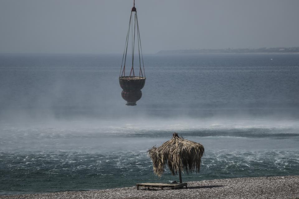 A helicopter fills water from the sea during a wildfire, near Gennadi village, on the Aegean Sea island of Rhodes, southeastern Greece, on Thursday, July 27, 2023. The wildfires have raged across parts of the country during three successive Mediterranean heat waves over two weeks, leaving five people dead. (AP Photo/Petros Giannakouris)