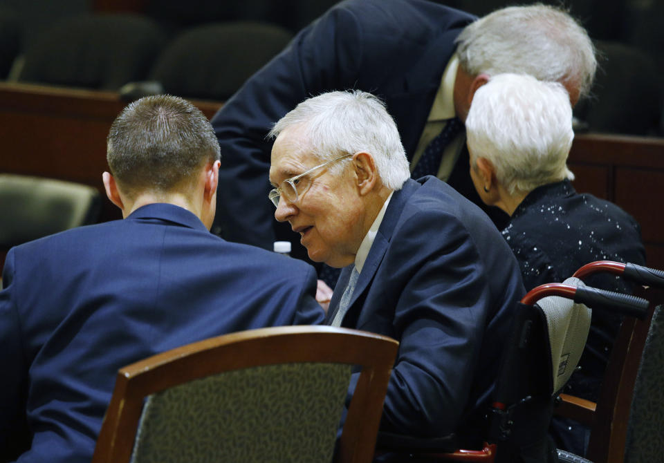 Former U.S. Sen. Harry Reid, second from left, sits in court Tuesday, March 26, 2019, in Las Vegas. A jury in Nevada heard opening arguments Tuesday in Reid's lawsuit against the maker of a flexible exercise band that he says slipped from his hand while he used it in January 2015, causing him to fall and suffer lasting injuries including blindness in one eye. (AP Photo/John Locher)