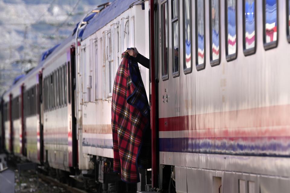 FILE - A man holds a blanket outside a train used as a shelter in Iskenderun city, southern Turkey, on Feb. 14, 2023. Hundreds of thousands of people are seeking shelter after the Feb. 6 earthquake in southern Turkey left homes unlivable. Many survivors have been unable to find tents or containers dispatched to the region by the government and aid agencies, Instead they have sought refuge in any structure that can protect them from the winter conditions, including greenhouses, rail carriages and factories. (AP Photo/Hussein Malla)