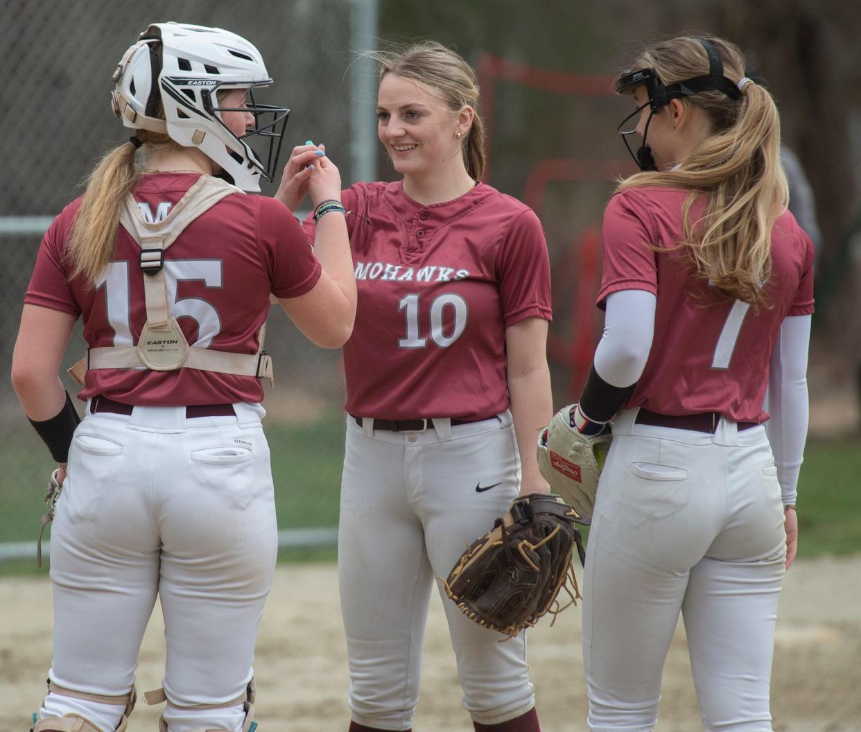 Millis High School catcher Emilia Leach, Isabelle Jewett, and pitcher Riley Caufield in between innings against Millis, April 10, 2024.