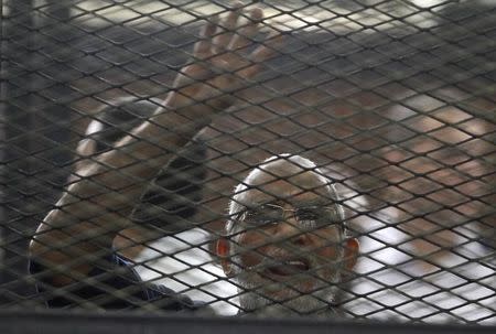 Muslim Brotherhood's General Guide Mohamed Badie shouts slogans and gestures the four-fingered "Rabaa" hand symbol from the defendant's cage in a courtroom in Cairo June 7, 2014. REUTERS/Mohamed Abd El Ghany