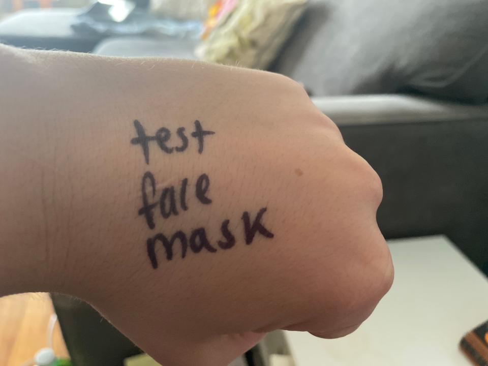 A hand with black marker on it that says "test face mask."