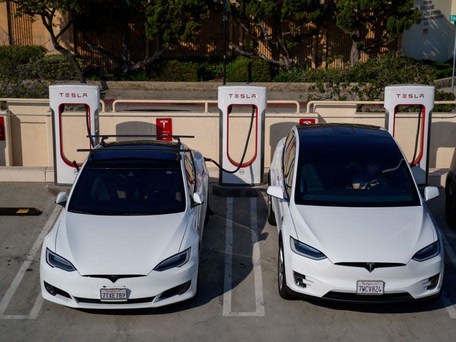 Two Tesla vehicles at a Supercharger station.