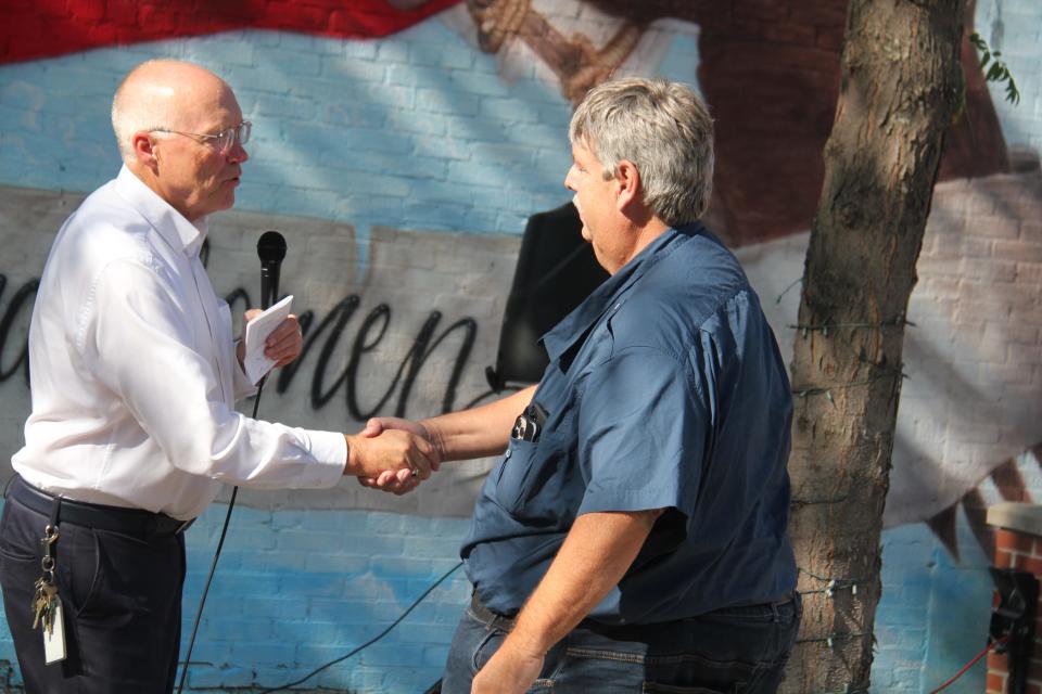 Superintendent Clark Wicks shakes hands with Troy Griffith, who recently received the 2023 Tom Horn Memorial Award from the Iowa Pupil Transportation Association, during Back to School Night at the Perry Farmers Market on Thursday, Aug. 17, 2023.