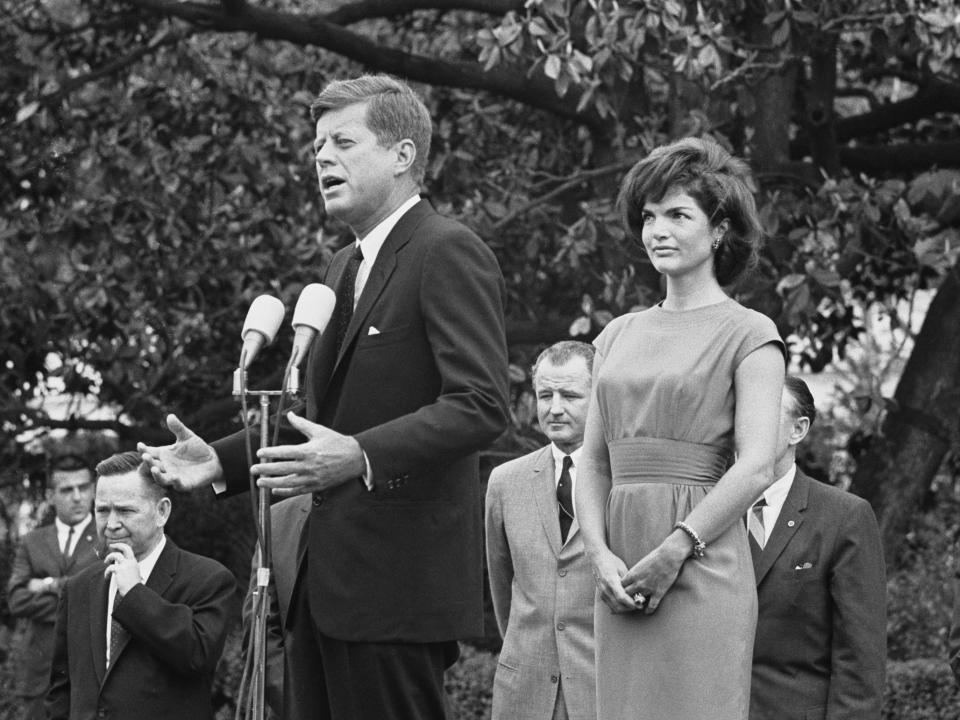 President John F. Kennedy, accompanied by First Lady Jackie Kennedy, speaks to delegates on the South Lawn of the White House.