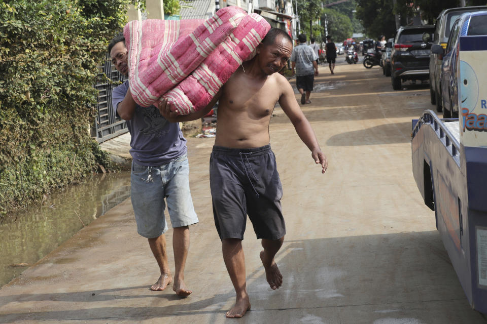 Residents carry a mattresses from their flooded homes in Tanggerang on the outskirts of Jakarta, Indonesia, Friday, Jan. 3, 2020. Severe flooding in greater Jakarta has killed scores of people and displaced tens of thousands others, the country's disaster management agency said. (AP Photo/Tatan Syuflana)