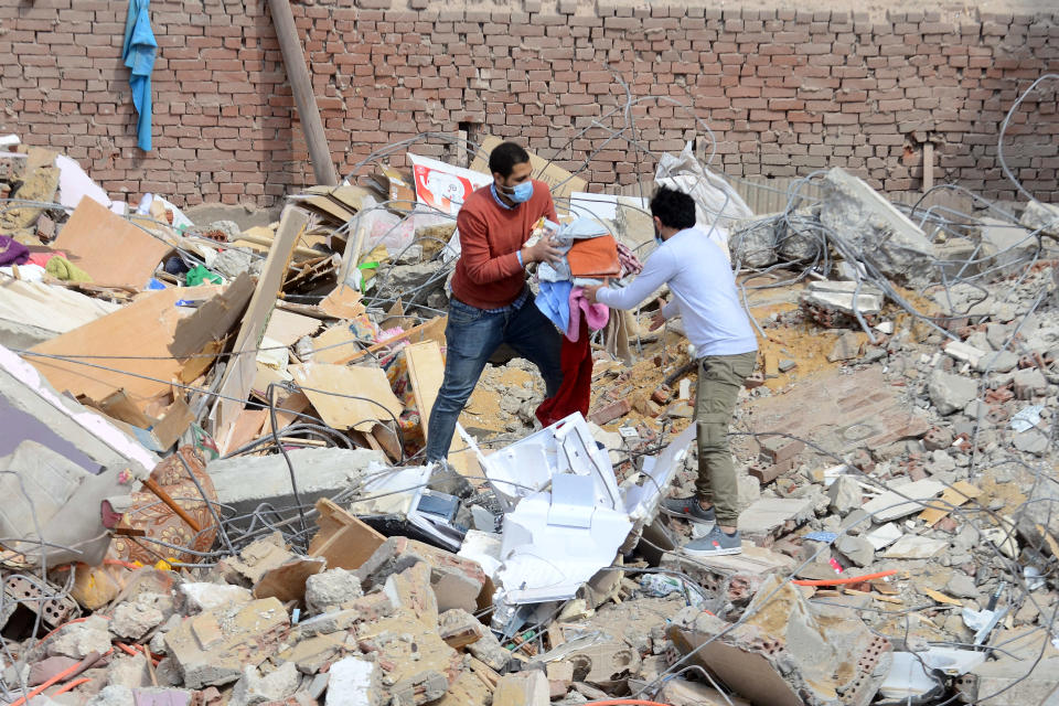 People carry their belongings on the rubble of a collapsed apartment building in the el-Salam neighborhood, in Cairo, Egypt, Saturday, March 27, 2021. A nine-story apartment building collapsed in the Egyptian capital early Saturday, killing at several and injuring about two dozen others, an official said. (AP Photo/Tarek wajeh)