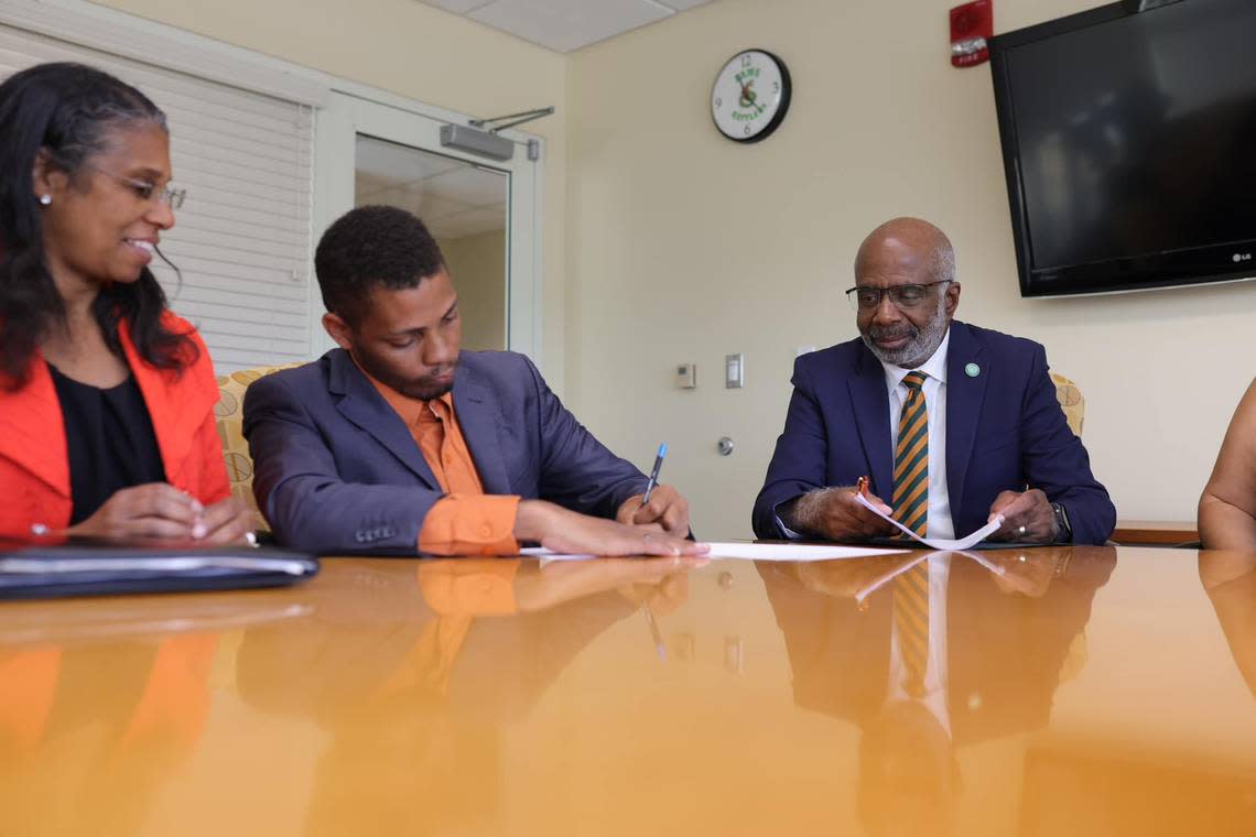 Gregory Gerami (middle), president and CEO of Batterson Farms Corp, signs documents next to Florida A&M University President Larry Carter (right). Gerami recently announced a $237 million donation to Florida A&M University, the largest ever for a historically Black college or university. But many are skeptical after a similar donation he pledged to Coastal Carolina University in 2020 collapsed.