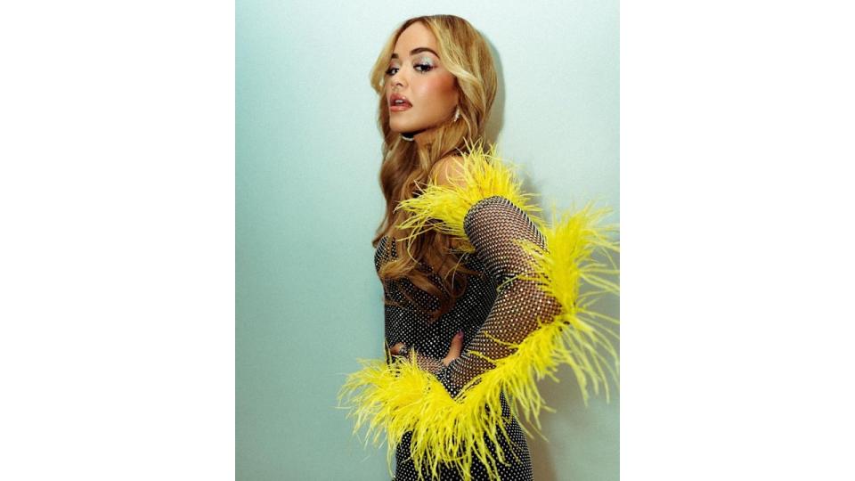 Rita Ora wearing a black diamante outfit with yellow feathers