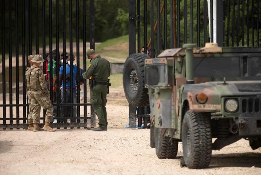 Migrants waited at a gate last summer near the U.S.-Mexico border in Del Rio. The group surrendered to the National Guard and U.S. Customs and Border Protection.