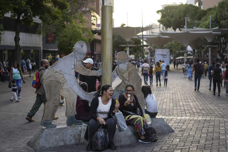 Mujeres comen helado cerca de la escultura "Petroleros" de Beatriz Blanco en Caracas