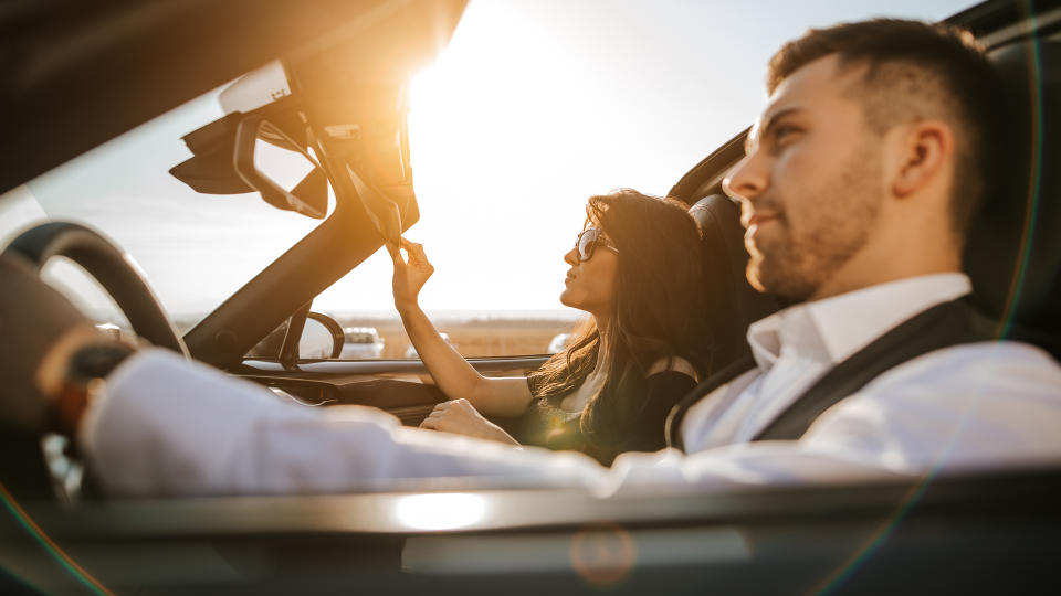 couple driving convertible new car at sunset