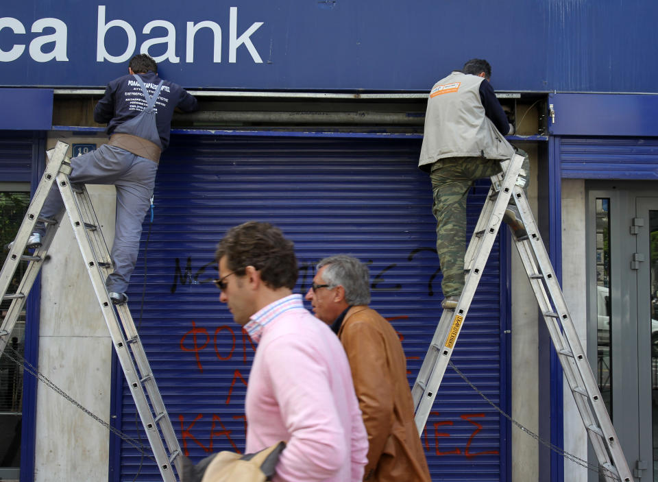 Workers fix a metal shutter of a bank branch in Athens, Friday, April 20, 2012. Greek banks will publish their annual reports later Friday, which are expected to include severe losses resulting from their participation in the country's massive private debt writedown earlier this year. (AP Photo/Thanassis Stavrakis)