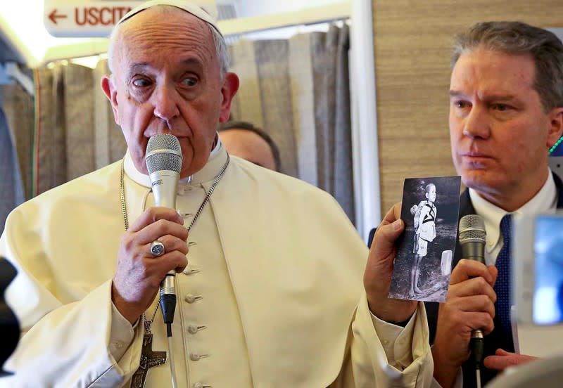 FILE PHOTO: Pope Francis holds a picture depicting a victim of the 1945 atomic bombing in Nagasaki as he speaks to reporters onboard the plane for his trip to Chile and Peru