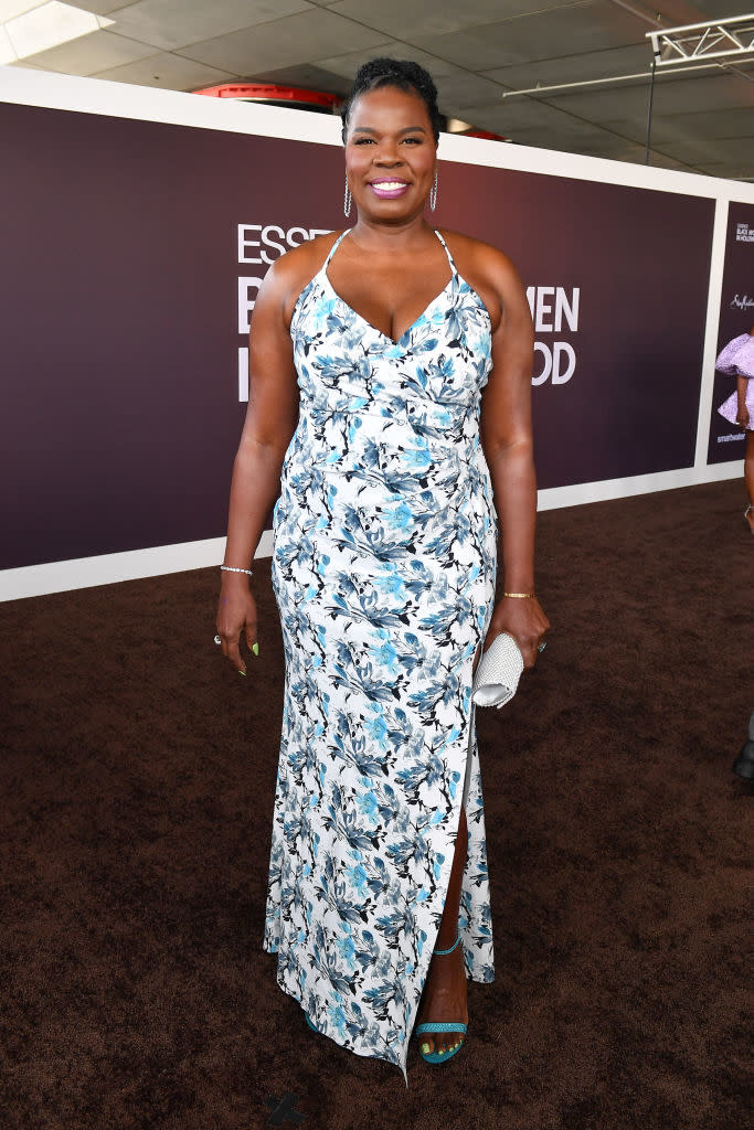 Leslie smiles on the red carpet in a floral patterned halter gown and holds a clutch