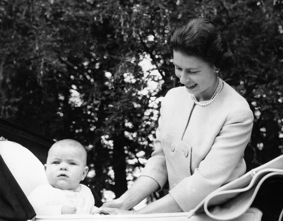 Alert Prince Andrew sits up in his carriage as his mother, Queen Elizabeth II, smiles down at him, when the baby prince was nearing his seventh month birthday, Sept. 13, 1960. (AP Photo)