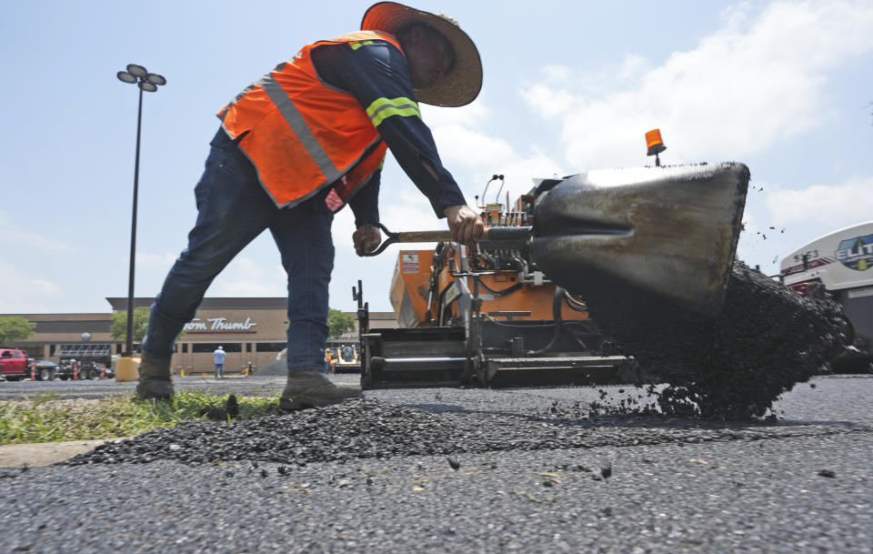 Miguel, no last name given, shovels hot asphalt during a parking lot resurfacing job in Richardson, Texas, Tuesday, June 20, 2023. (AP Photo/LM Otero)