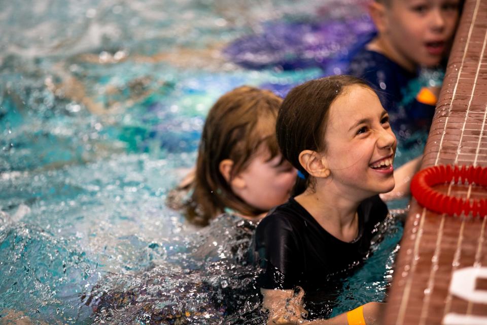 Children smile as and kick their feet during the "World's Largest Swim Lesson" at Holland Aquatic Center.