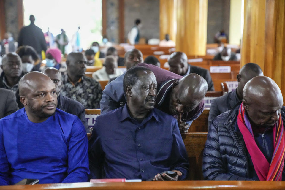 An aide of Presidential candidate Raila Odinga speaks to him as he attends Sunday mass in St. Francis church in Nairobi, Kenya, Sunday, Aug. 14, 2022. The race remains close between Odinga and Deputy President William Ruto as the electoral commission physically verifies more than 46,000 results forms electronically transmitted from around the country. (AP Photo/Mosa'ab Elshamy)