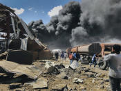 People are seen in front of clouds of black smoke from fires in the aftermath at the scene of an airstrike in Mekele, the capital of the Tigray region of northern Ethiopia Wednesday, Oct. 20, 2021. New airstrikes have hit Mekele, residents said Wednesday, as Ethiopia's government said it was targeting facilities to make and repair weapons, which a spokesman for the rival Tigray forces denied. (AP Photo)