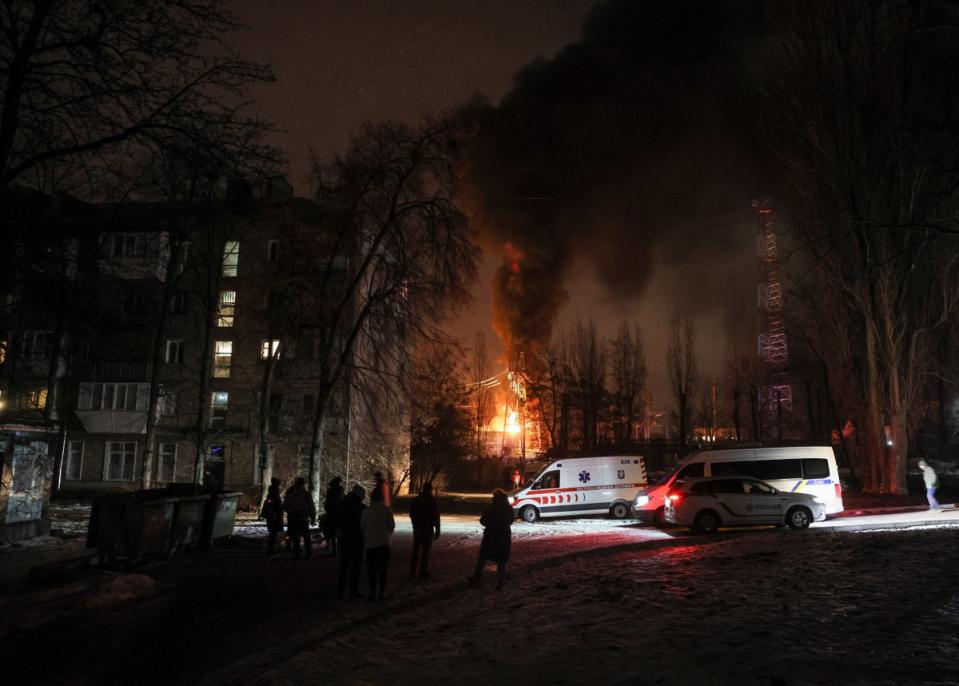 Des résidents locaux se rassemblent près d'un immeuble résidentiel alors qu'un objet d'infrastructure électrique critique brûle après une attaque de drone russe, au milieu de l'attaque de la Russie contre l'Ukraine à Kyiv (REUTERS)