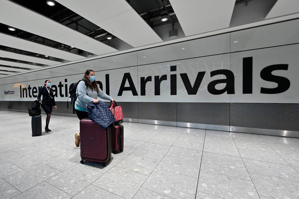 Passengers arrive with lugagge at the Terminal 5 international arrivals hall at London Heathrow Airport