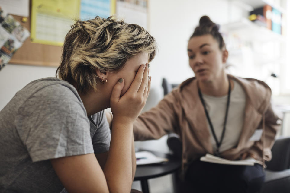 Woman comforting someone who appears stressed or upset, in a casual indoor setting