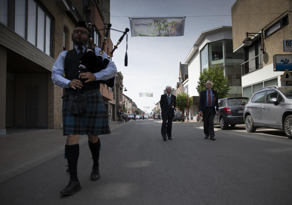 A bagpiper escorts British RAF veteran George Sutherland, 98, center, and his son Alex Sutherland as they take part in a VE Day charity walk to raise funds for Talbot House in Poperinge, Belgium, Friday, May 8, 2020. Sutherland walked from the Lijssenthoek war cemetery to Talbot house to raise money for the club which is currently closed due to coronavirus lockdown regulations. The club, founded in 1915 was a place for British soldiers to rest during both the First and Second World Wars. (AP Photo/Virginia Mayo)