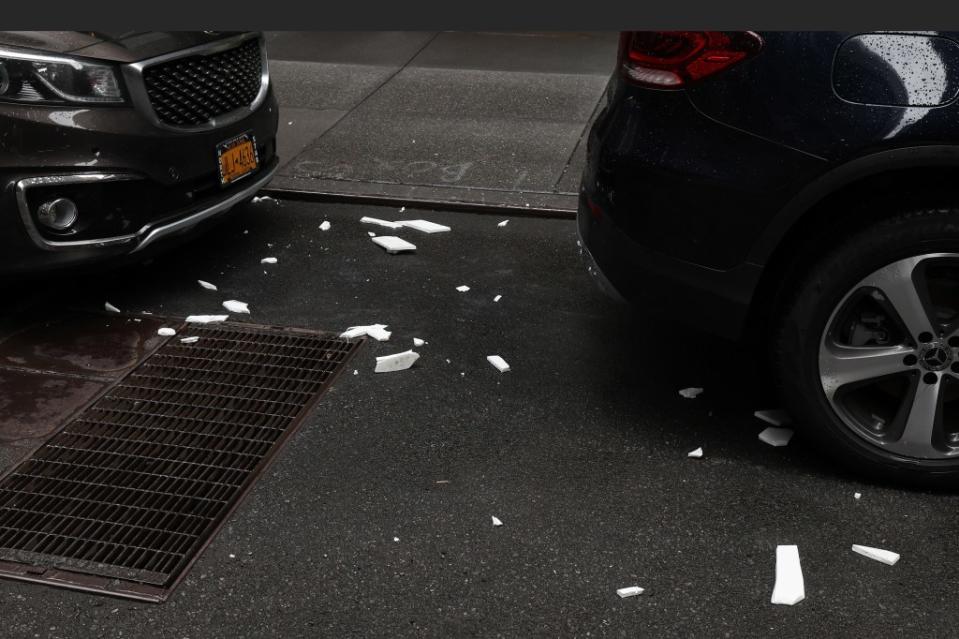 Broken tiles seen on the street near parked cars. William Farrington