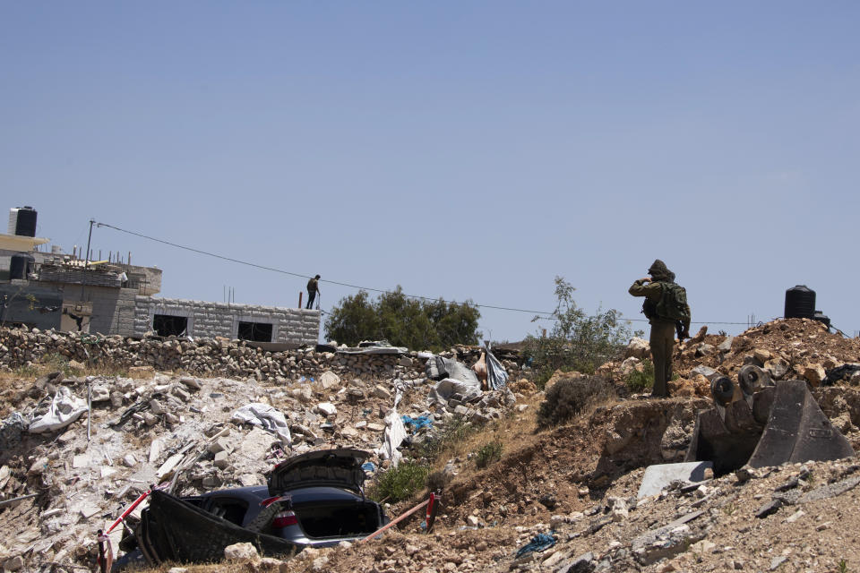 An Israeli soldier stands near a car said to be used in an attack near Hizmeh Junction in the West Bank, Wednesday, June 16, 2021. The Israeli military on Wednesday shot and killed a Palestinian woman who it said tried to ram her car into a group of soldiers guarding a West Bank construction site. (AP Photo/Maya Alleruzzo)