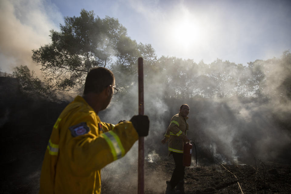 Firefighters attempt to extinguish a fire started by an incendiary device launched from the Gaza Strip, in Kibbutz Kfar Aza on the border with Gaza, Monday, Aug. 24, 2020. Militants affiliated with Hamas have launched scores of incendiary balloons into southern Israel in recent weeks in a bid to pressure Israel to ease the blockade imposed since Hamas took control of the territory in 2007. (AP Photo/Ariel Schalit)