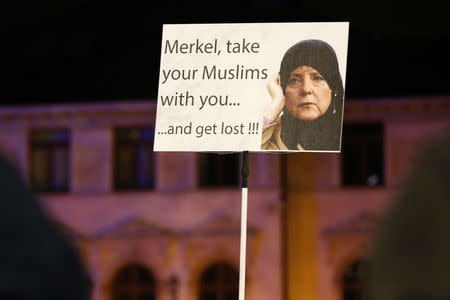 Members of LEGIDA, the Leipzig arm of the anti-Islam movement PEGIDA, hold a poster depicting German Chancellor Angela Merkel during a rally in Leipzig, Germany January 11, 2016. REUTERS/Fabrizio Bensch