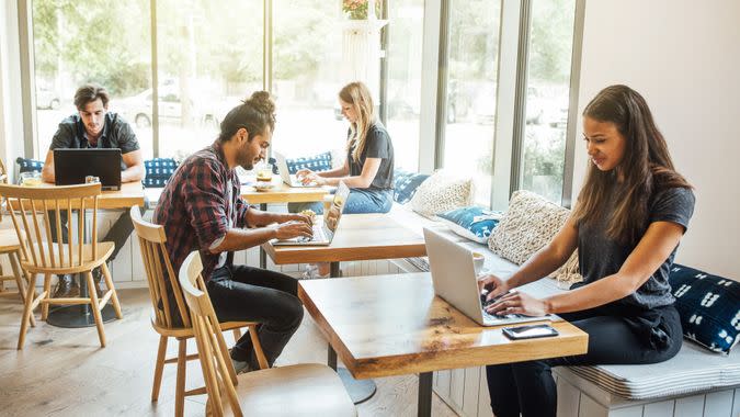 Young people sitting at cafe table working on laptop computers.