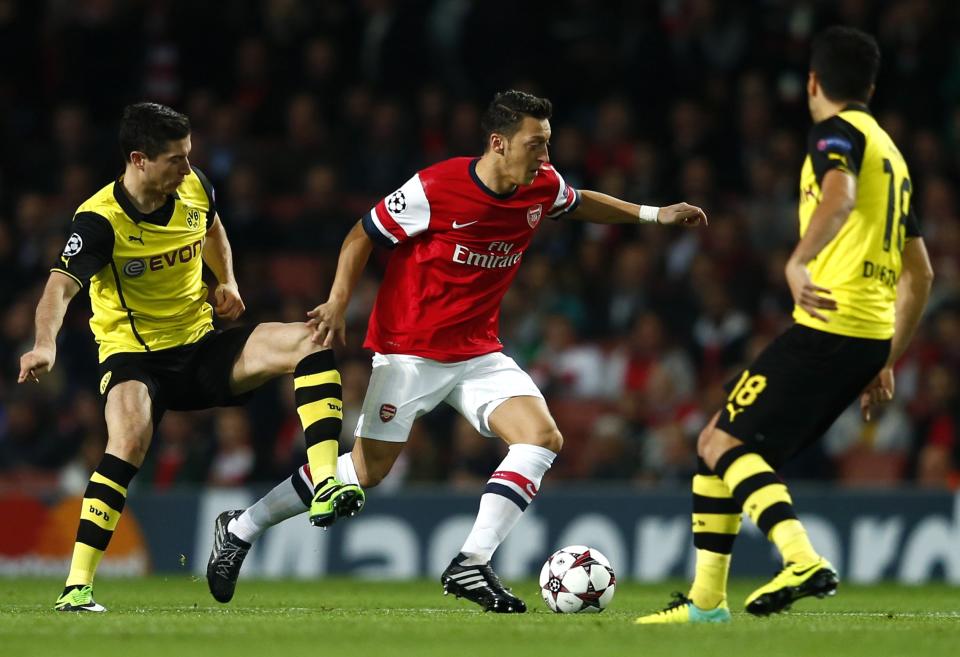 Arsenal's Mesut Ozil (C) is challenged by Borussia Dortmund's Henrikh Mkhitaryan (L) and Nuri Sahin during their Champions League soccer match at the Emirates stadium in London October 22, 2013. REUTERS/Eddie Keogh (BRITAIN - Tags: SPORT SOCCER)