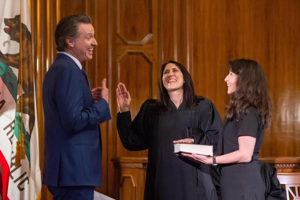 The new Chief Justice Patricia Guerrero, center, shares a laugh with Gov. Gavin Newsom, and her sister Claudia Pearson, during her swearing-in ceremony Monday at the Stanley Mosk Library and Courts Building in downtown Sacramento.