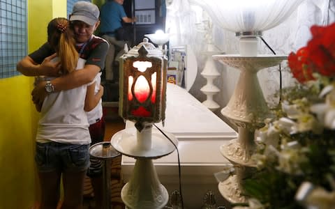 Saldy Delos Santos, father of Kian Loyd, who was killed allegedly in a shootout with police, comforts his son's girlfriend - Credit: AP Photo/Bullit Marquez