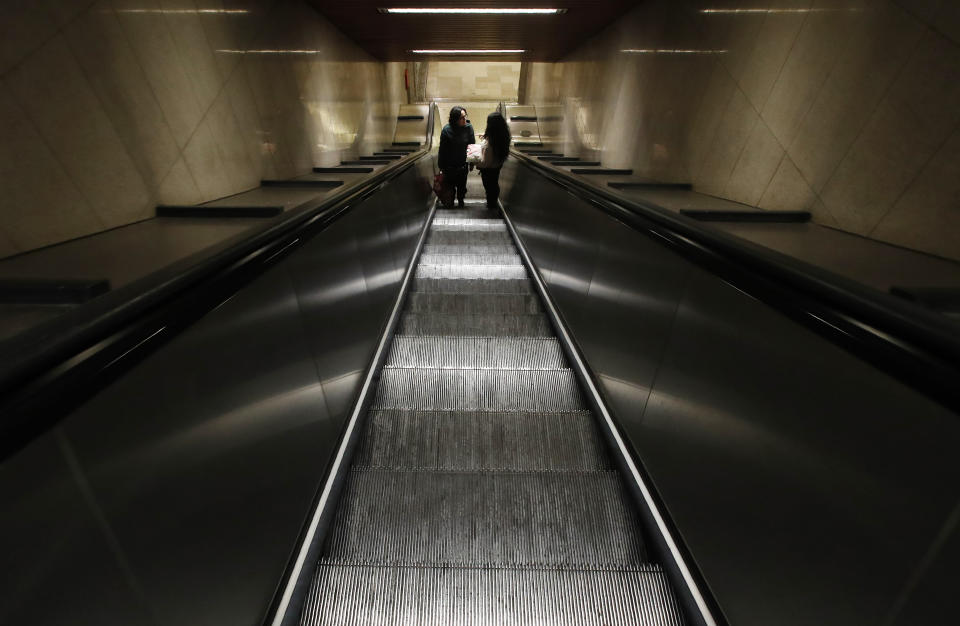 Two people stand in an empty staircase leading to the subway, in Milan, northern Italy, Wednesday, Feb. 26, 2020. Italy has been struggling to contain the rapidly spreading outbreak that has given the country more coronavirus cases outside Asia than anywhere else. (AP Photo/Antonio Calanni)