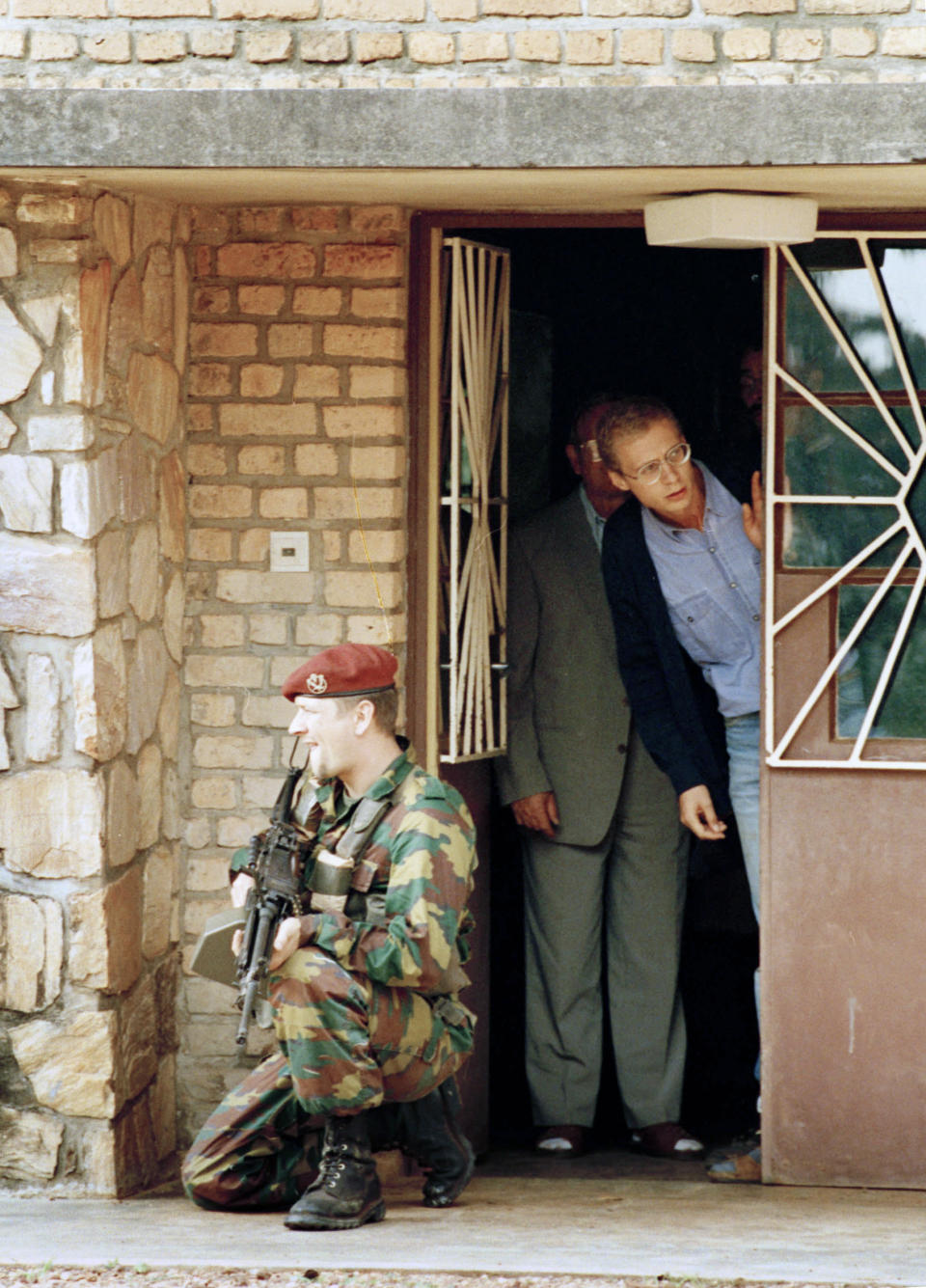 FILE - A Belgian soldier guards the front of a house, where Belgians wait to be evacuated out of Kigali, Rwanda, April 13, 1994. Belgian forces rescued several Belgians who lived in a compound in the Rwanda capital, running the Ndere psychiatric hospital. (AP Photo/Karsten Thielker, File)