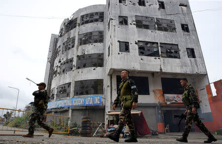 Soldiers walk past a damaged building after government troops cleared the area. REUTERS/Romeo Ranoco