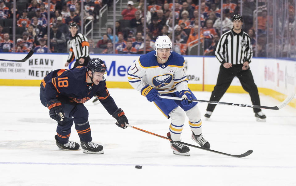 Buffalo Sabres' JJ Peterka (77) and Edmonton Oilers' Zach Hyman (18) battle for the puck during first-period NHL hockey game action in Edmonton, Alberta, Thursday March 21, 2024. (Jason Franson/The Canadian Press via AP)