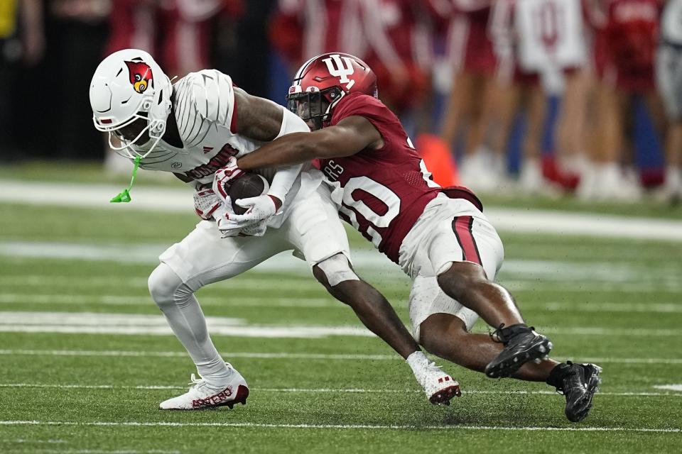 Louisville wide receiver Ahmari Huggins-Bruce is tackled by Indiana defensive back Louis Moore during the second half of an NCAA college football game, Saturday, Sept. 16, 2023, in Indianapolis. (AP Photo/Darron Cummings)