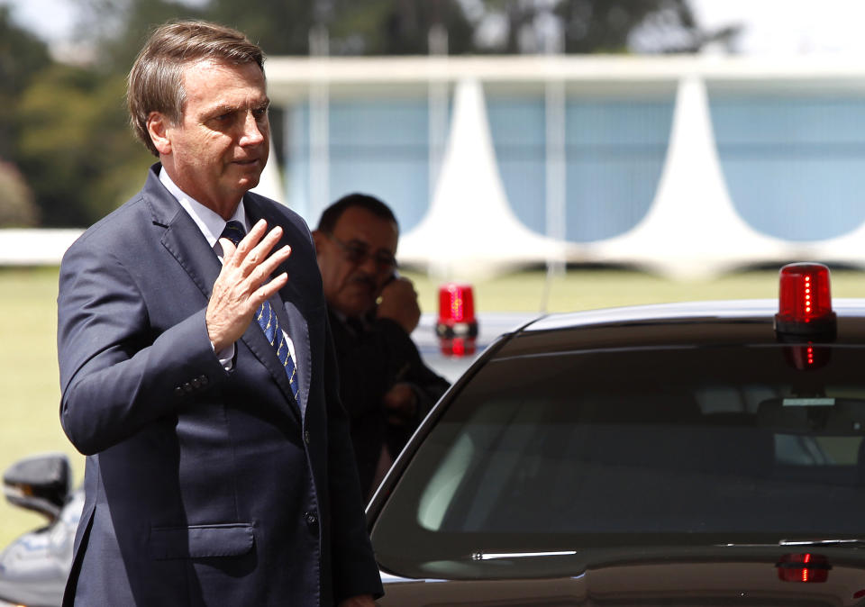 Brazil's President Jair Bolsonaro waves as he leaves the presidential residence Alvorada Palace, after learning that he tested negative for the new coronavirus, in Brasilia, Brazil, Friday, March 13, 2020. Concern about Bolsonaro’s exposure to the coronavirus — and possibly that of U.S. President Donald Trump — had grown after confirmation that the Brazilian leader’s communications director tested positive. The senior official had joined Bolsonaro just days earlier at a meeting with Trump and senior aides in Florida. (AP Photo/Beto Barata)