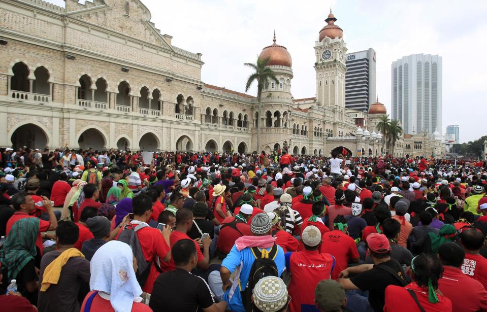 Protesters sit in front of the historical building of Sultan Abdul Samad during a protest against the implementation of the Goods and Services Tax (GST) in Kuala Lumpur, Malaysia, Thursday, May 1, 2014. (AP Photo/Lai Seng Sin)