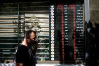 An Iranian man talks on the phone as he walks past an electronic currency board in Tehran