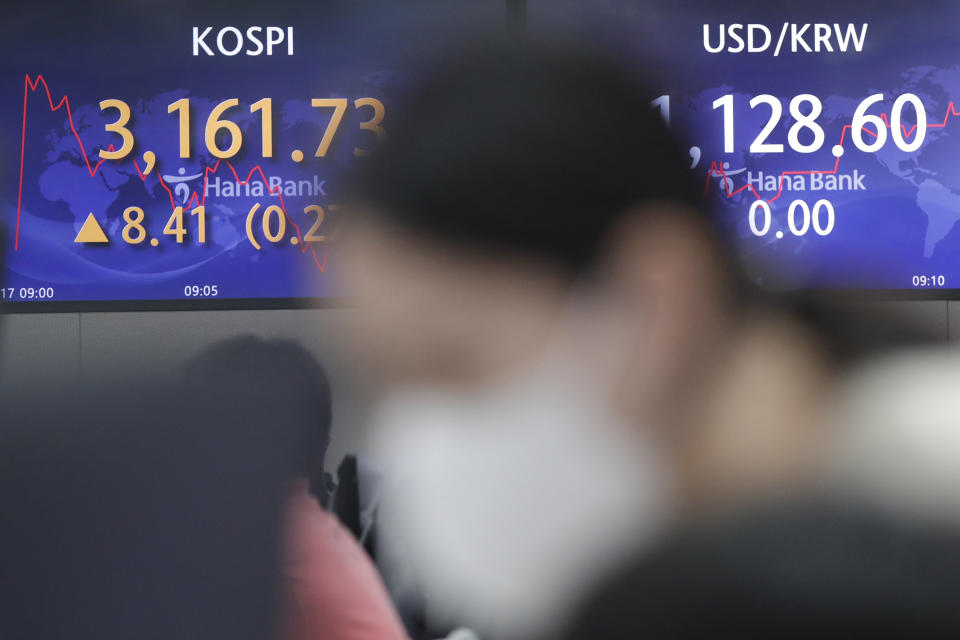 A currency trader watches computer monitors near screens showing the Korea Composite Stock Price Index (KOSPI), left, and the foreign exchange rate between U.S. dollar and South Korean won at a bank's foreign exchange dealing room in Seoul, South Korea, Monday, May 17, 2021. Asian stock markets were mixed Monday after Taiwan and Singapore tightened anti-coronavirus restrictions and Wall Street turned in its biggest weekly decline in three months. (AP Photo/Lee Jin-man)