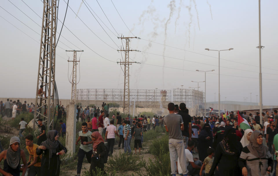 Protesters gather while others run to cover from teargas fired by Israeli soldiers during a protest at the entrance of Erez border crossing between Gaza and Israel, in the northern Gaza Strip, Tuesday, Sept. 4, 2018. The Health Ministry in Gaza says several Palestinians were wounded by Israeli fire as they protested near the territory's main personnel crossing with Israel. (AP Photo/Adel Hana)