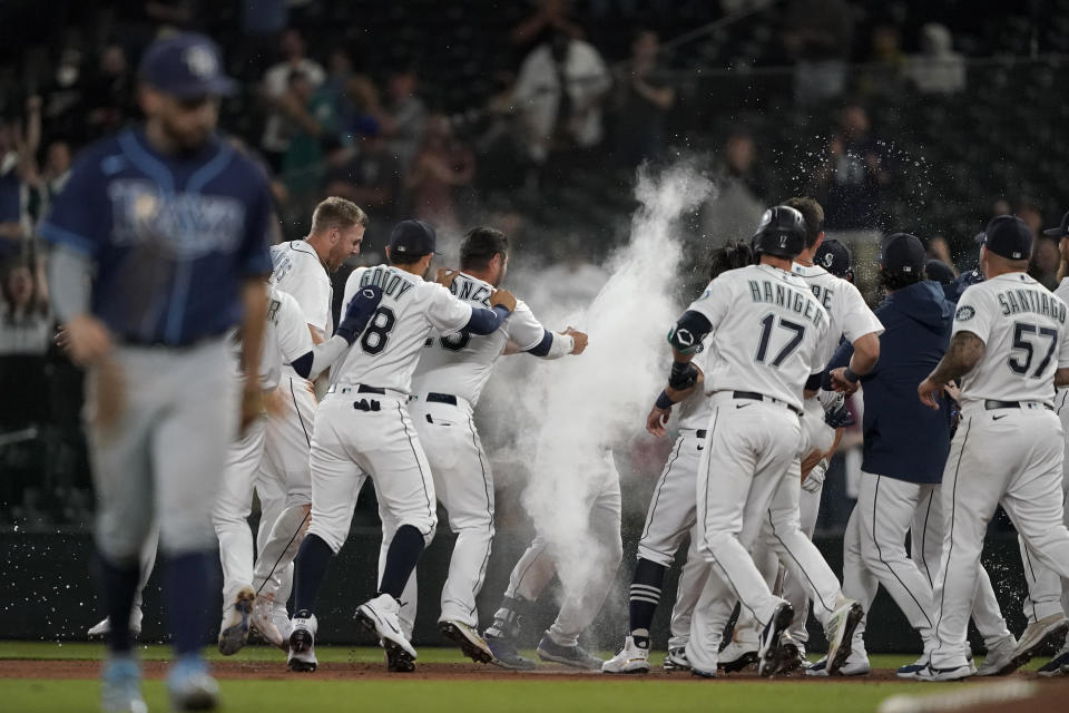 Seattle Mariners' Kyle Seager, center, is covered in powder by teammates after after he drove in the winning run with a single in the ninth inning of the team's baseball game against the Tampa Bay Rays, Thursday, June 17, 2021, in Seattle. Rays' Brandon Lowe, foreground left, heads off the field. The Mariners won 6-5. AP Photo/Ted S. Warren)